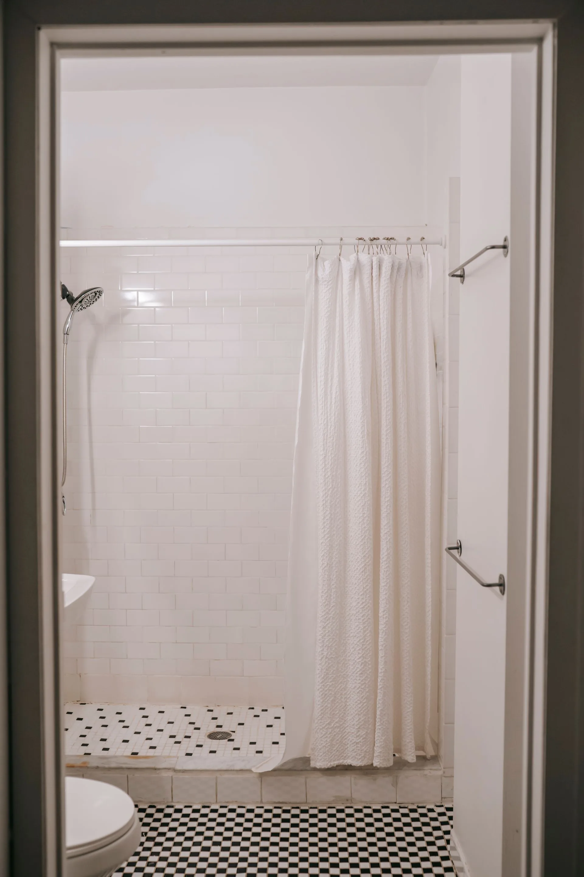 Minimalist bathroom with white shower curtain and tiled floor