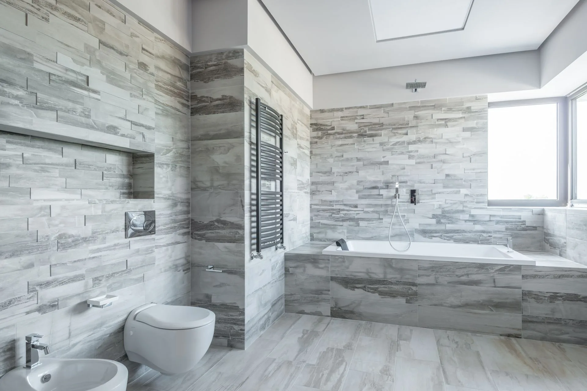 Gray and white tiled bathroom with sleek bathtub