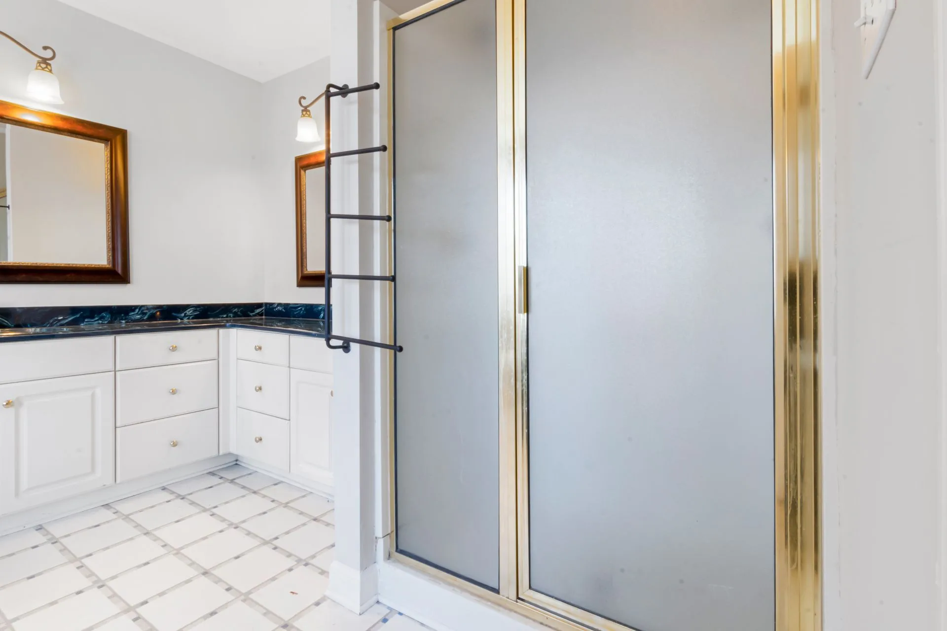 Bathroom with glass shower, gold trim, and marble countertop