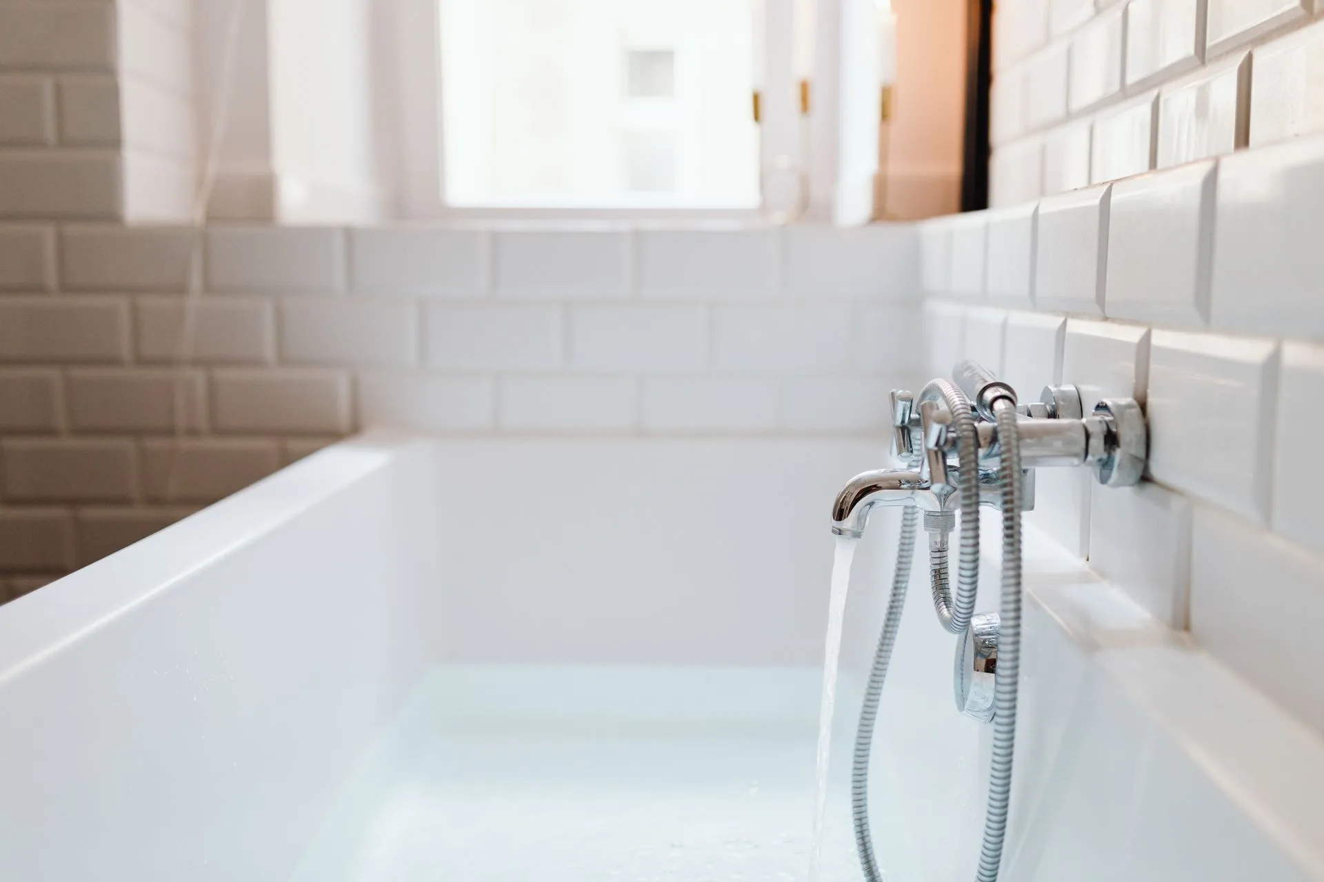 Chrome faucet and ceramic tiling in a sunlit bathroom