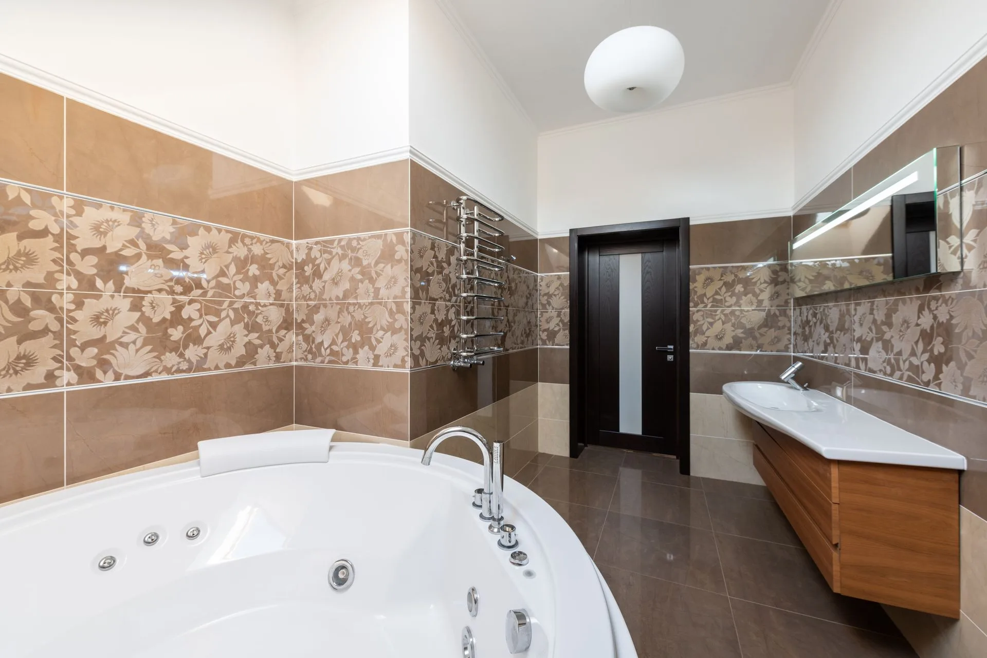 White bathtub with floral tile decor and wooden vanity